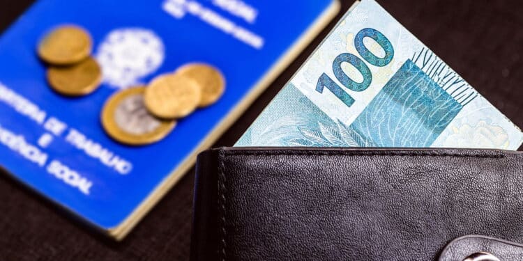 Banknotes of one hundred reais from brazil in black leather wallet isolated on black background, with old blurred work card from brazil