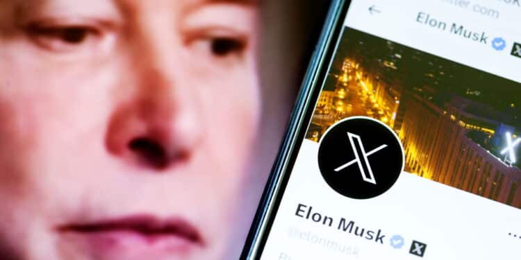 Elon Musks Twitter profile on a smartphone and Elon Musk in the background