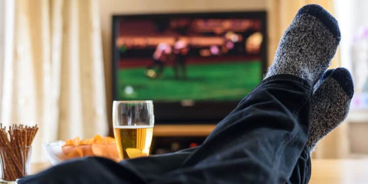 Television, TV watching (football match) with feet on table and huge amounts of snacks